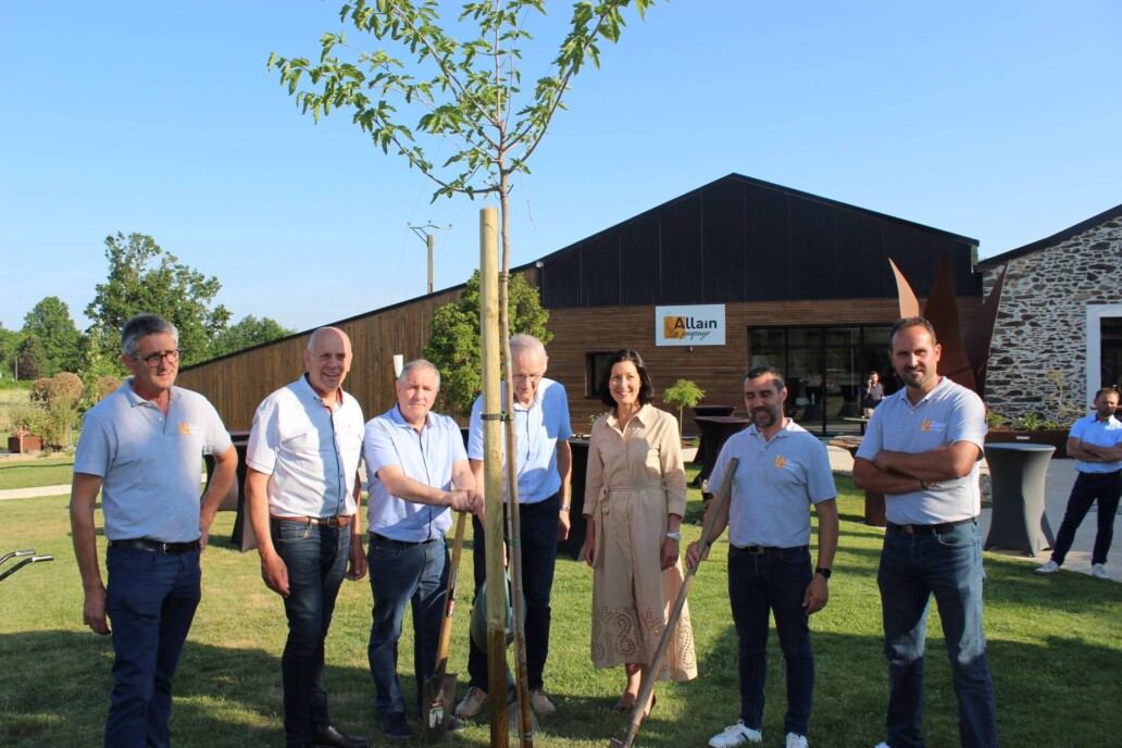 inauguration des nouveaux lieux de l'entreprise ALLAIN Paysage avec plantation d'un arbre symbolique. Sont pr&eacute;sents les 3 dirigeants de l'entreprise ainsi que des &eacute;lus locaux. On aper&ccedil;oit l'entreprise en fond avec mur en vieilles pierres & bardage bois.