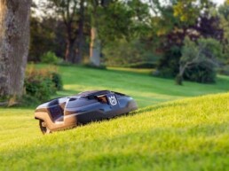 robot de tonte Husqvarna gris et noir en train de tondre dans une pente prononcée